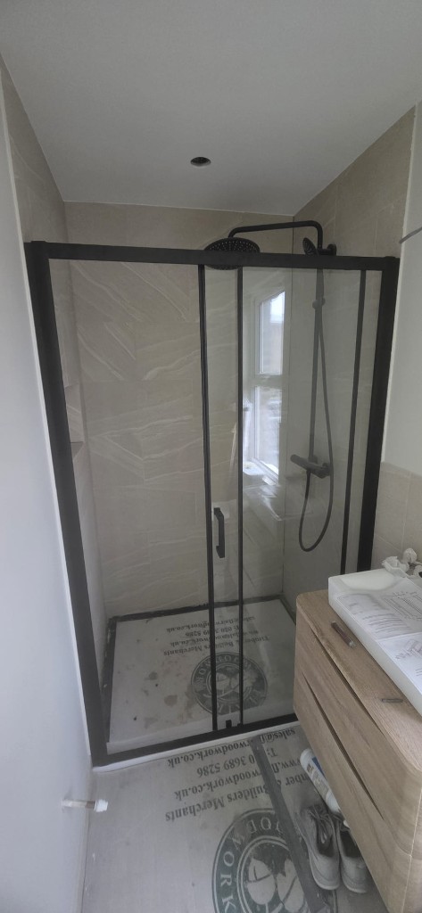 Modern bathroom shower installation with matte black frame and rainfall showerhead by Ikveles Construction