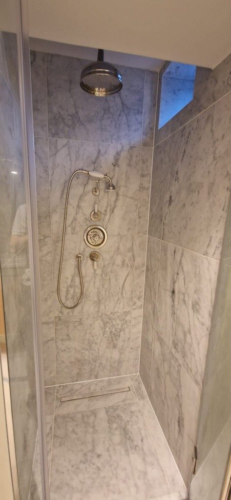 Luxury marble walk-in shower with rainfall head and chrome fittings by Ikveles Construction
