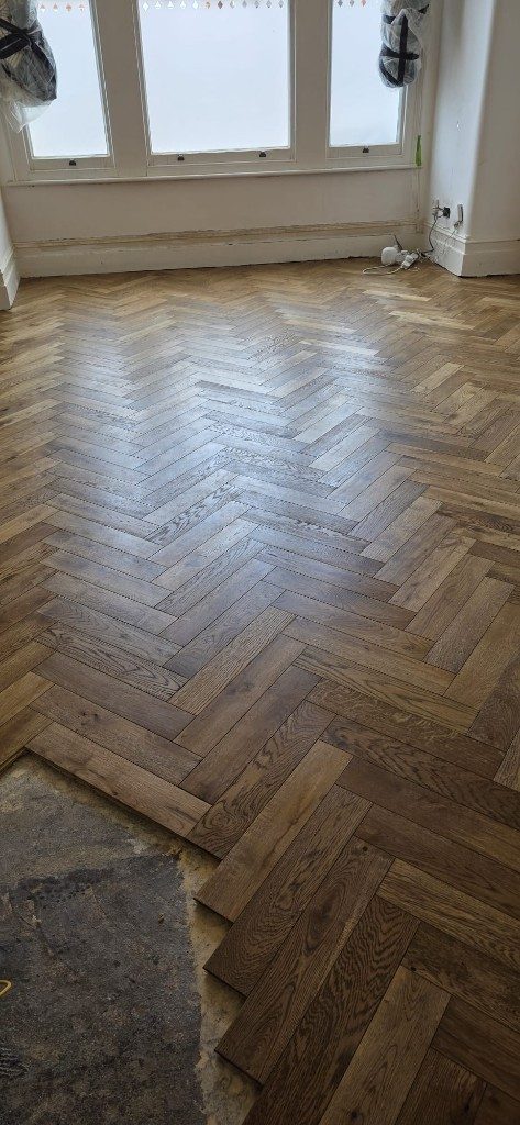 Herringbone flooring installation in a bay-window room by Ikveles Construction