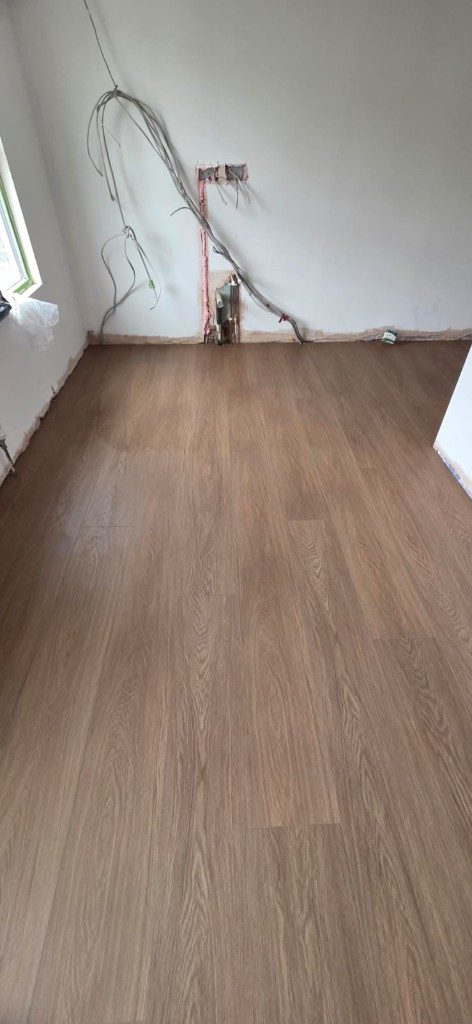 Oak-look plank flooring installation in a room under renovation by Ikveles Construction
