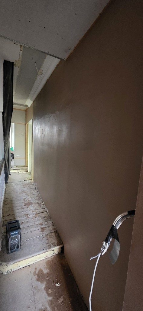 Freshly plastered hallway wall with a smooth finish by Ikveles Construction