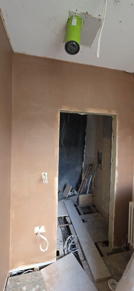 Interior plastering in progress with doorway and exposed wiring by Ikveles Construction