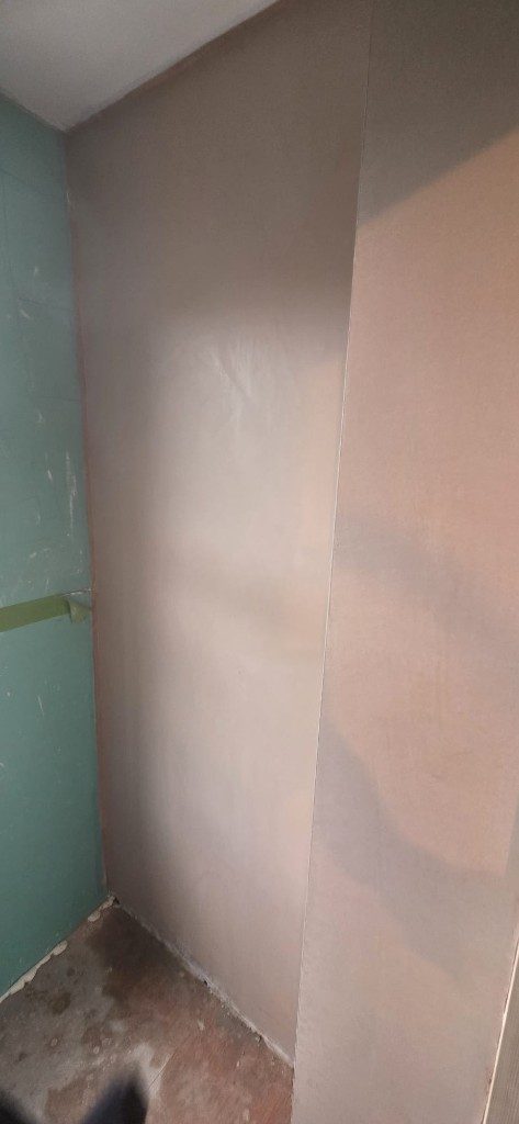 Fresh wet plaster skim next to plasterboard edge by Ikveles Construction